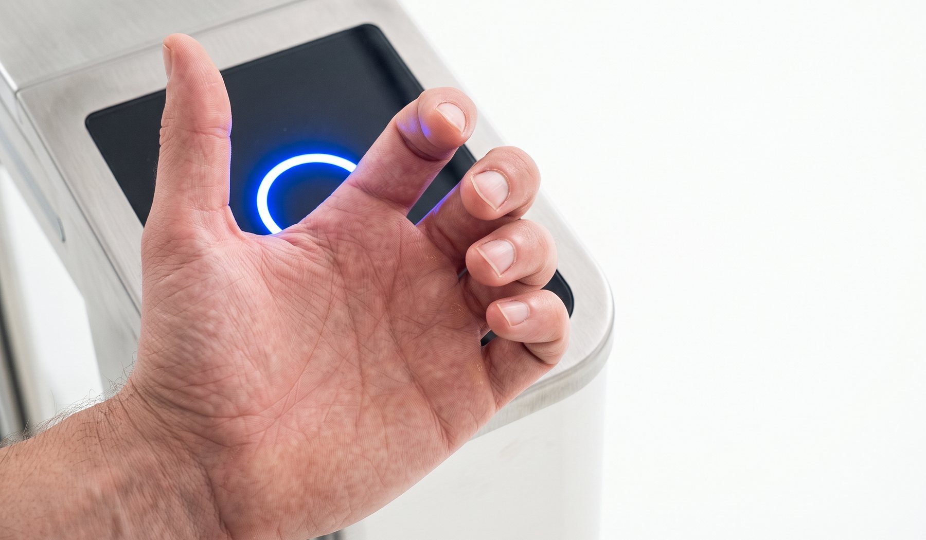 A hand held against the reader of an access gate, the reader ring lit blue